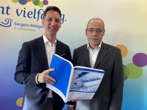 Landrat Andreas und Kreiskämmerer Thomas Damm halten ein dickes aufgeschlagenes Buch mit dem Entwurf des Kreishaushalts für 2024 in der Hand